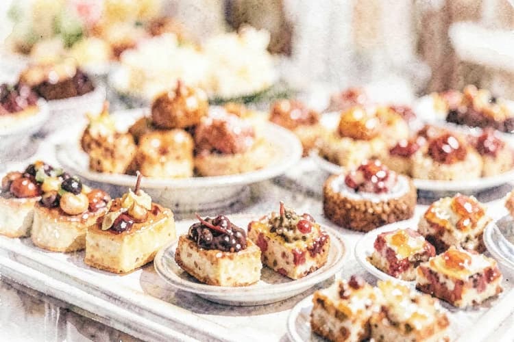 Pratos variados em uma mesa de buffet, com foco em salgados e doces.